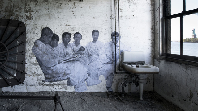 A large black-and-white photograph is attached to wall inside an dusty room overlooking the Statue of Liberty  
