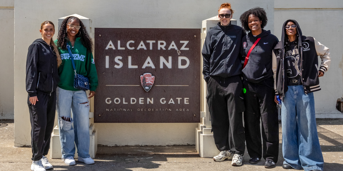 Five Golden State Valkyries players pose in front of the Alcatraz Island sign at the Golden Gate National Recreation Area.