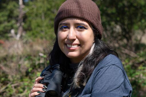 Portrait of birder Daniela Sánchez with binoculars on a birding trip.