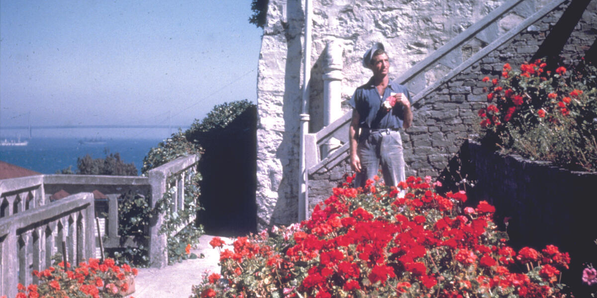 An Alcatraz inmate gardener stands in a rose garden on Officer's Row.