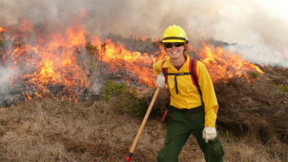 Alison Forrestel poses next to a grassland fire.