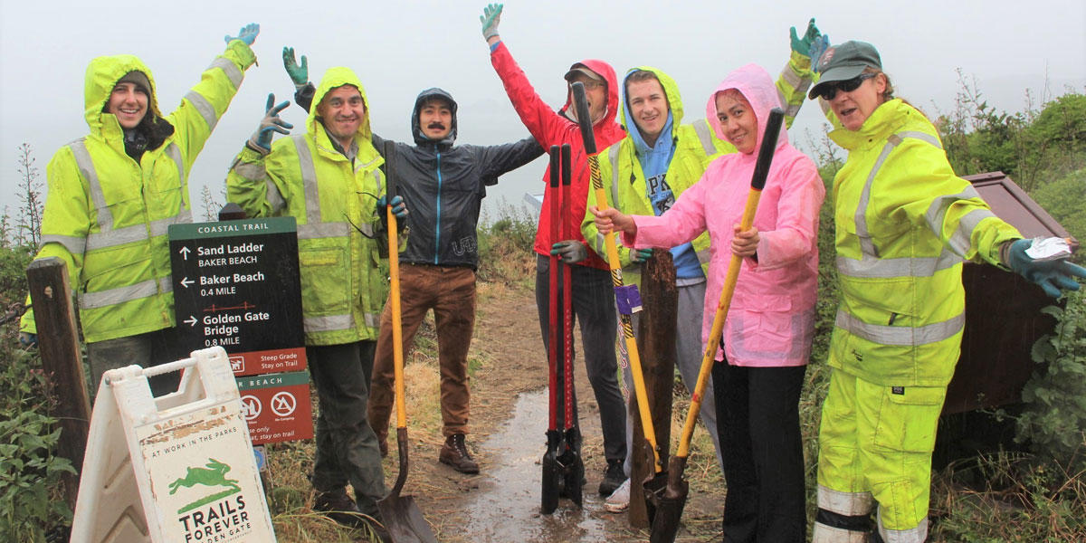 Volunteers in rain gear celebrate their hard work on the Coastal Trail.