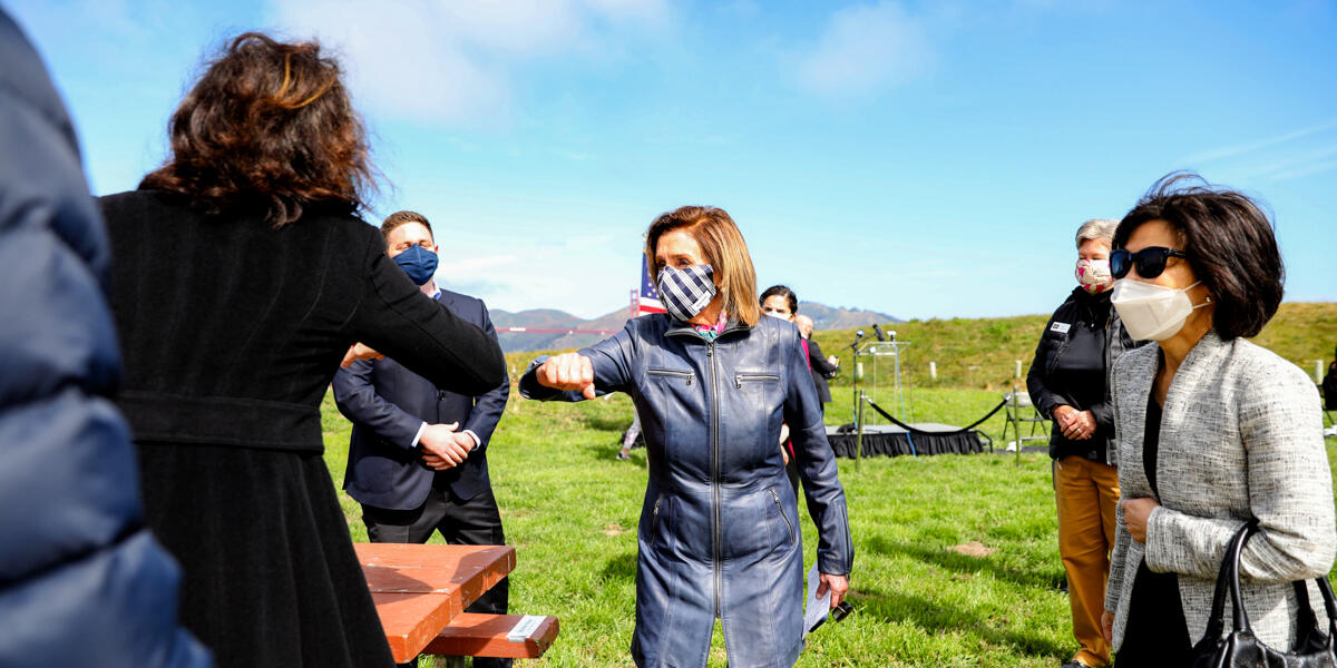 Speaker Nancy Pelosi elbow bumps to greet attendees at Crissy Field's 20th anniversary address