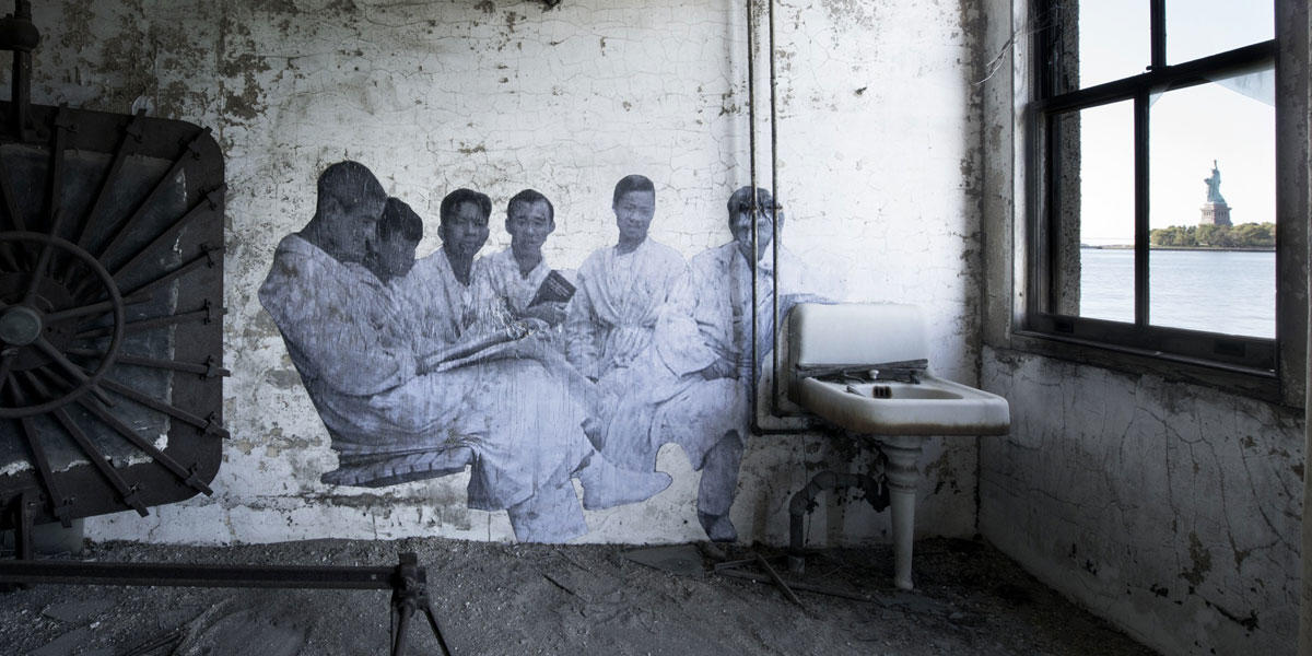 A large black-and-white photograph is attached to wall inside an dusty room overlooking the Statue of Liberty  