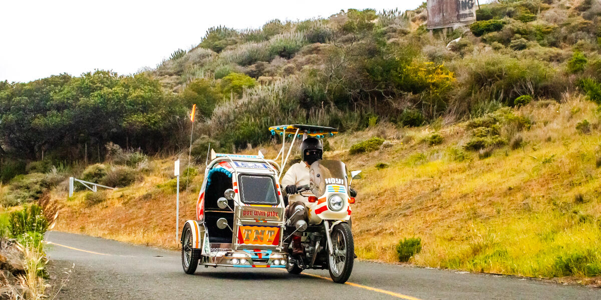 A motorcycle with a sidecar drives down a two-lane road.