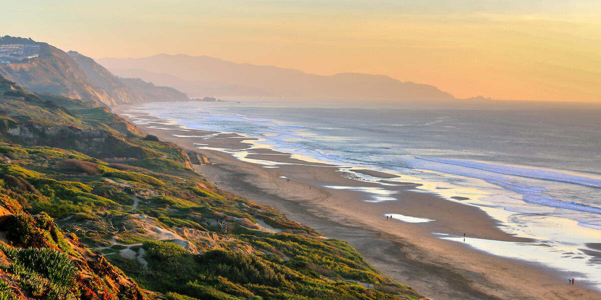 Scenic view overlooking the beach and bluffs of Fort Funston stretching out to the pacific ocean and gorgeous sunset