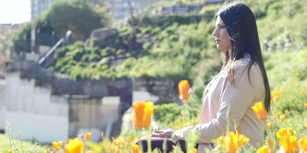 Sharaya Souza sits surrounded by orange poppies.