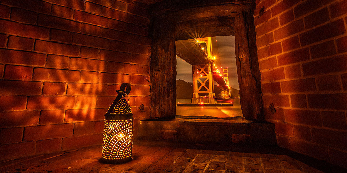 A lantern cast shadows on brick walls at Fort Point.