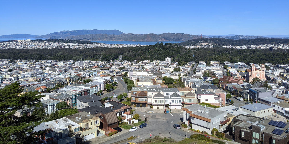 Buildings and cars next to a body of water with rolling hills in the distance