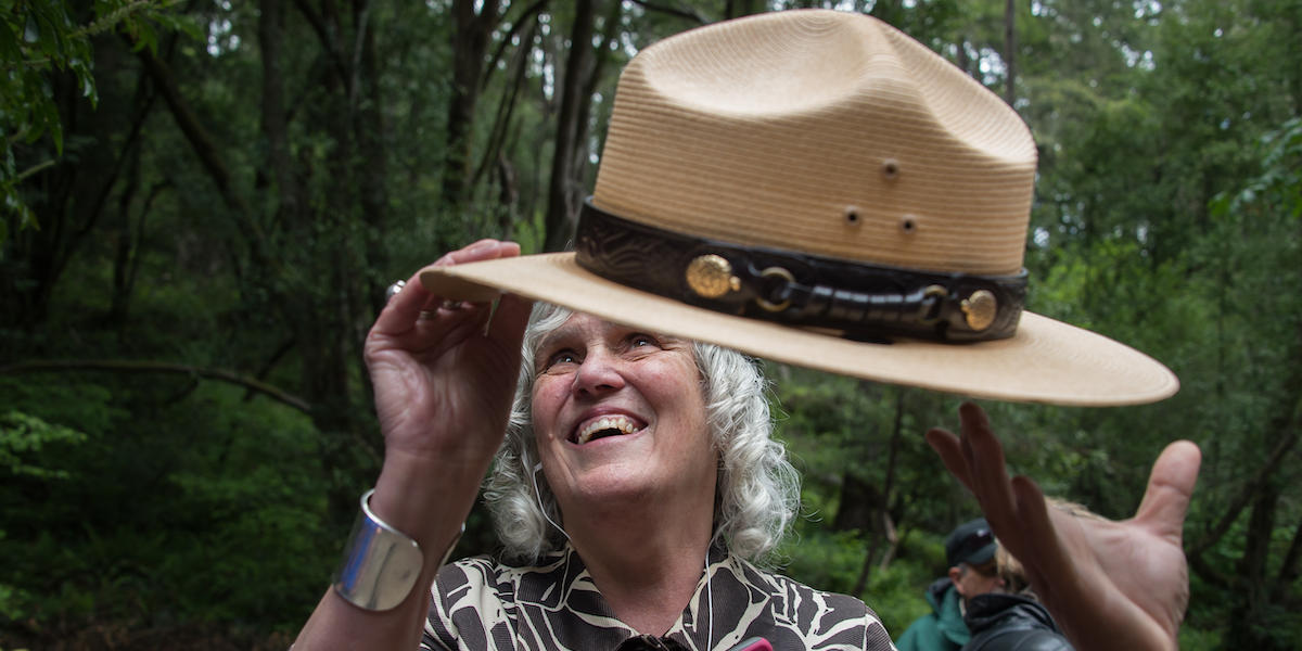 A visually impaired woman feels the NPS ranger hat. 