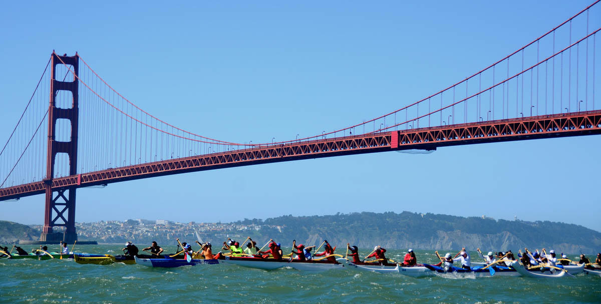 Outrigger canoes paddle under the Golden Gate Bridge.