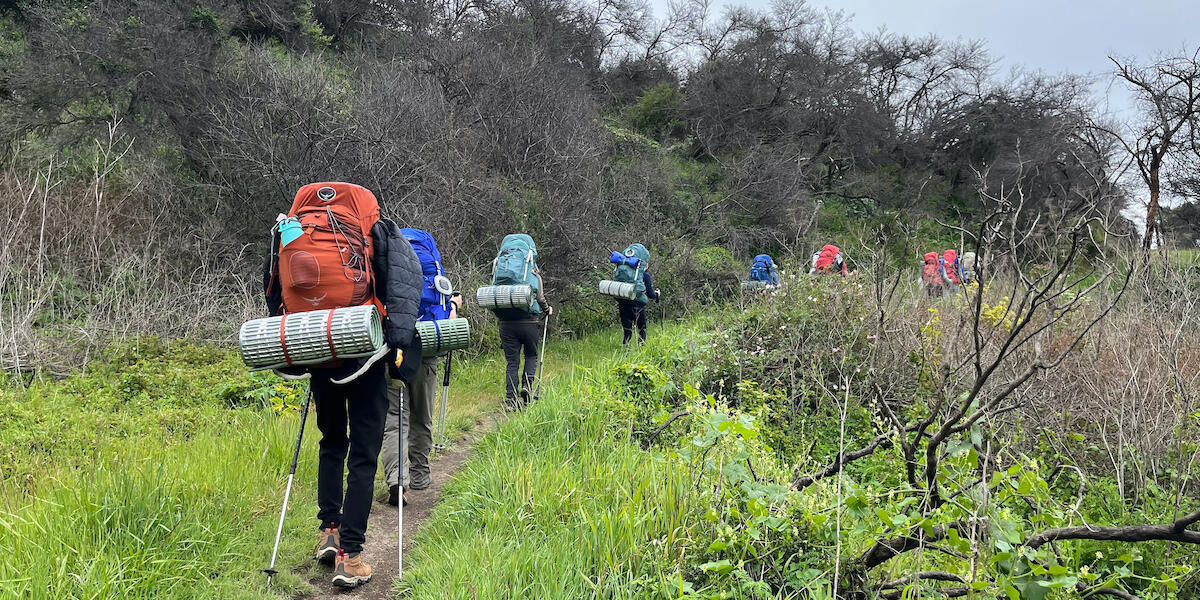 Group of youth backpacking along a trail.