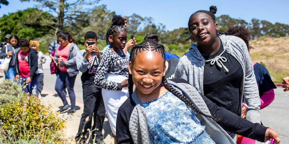 A youth group smiling as they hike through Presidio trails in San Francisco
