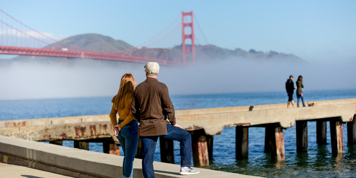 A couple stops to take in a Golden Gate Bridge view at Crissy Field East Beach