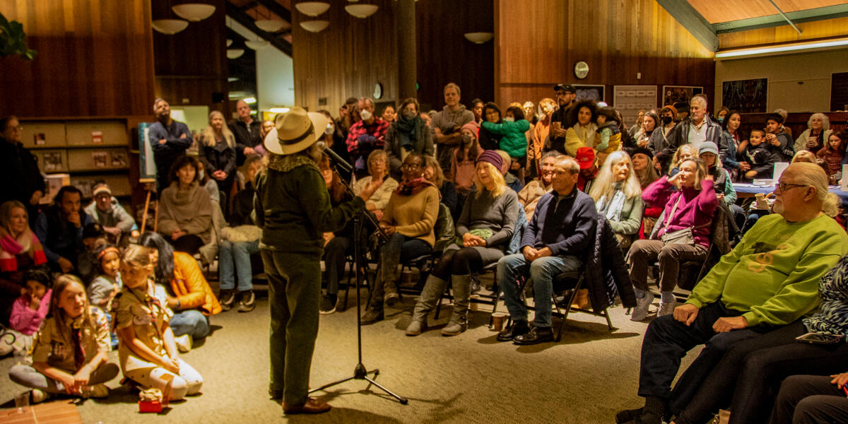 A National Park Service ranger speaks to a seated crowd in the Mill Valley Public Library during the Winter Solstice Celebration