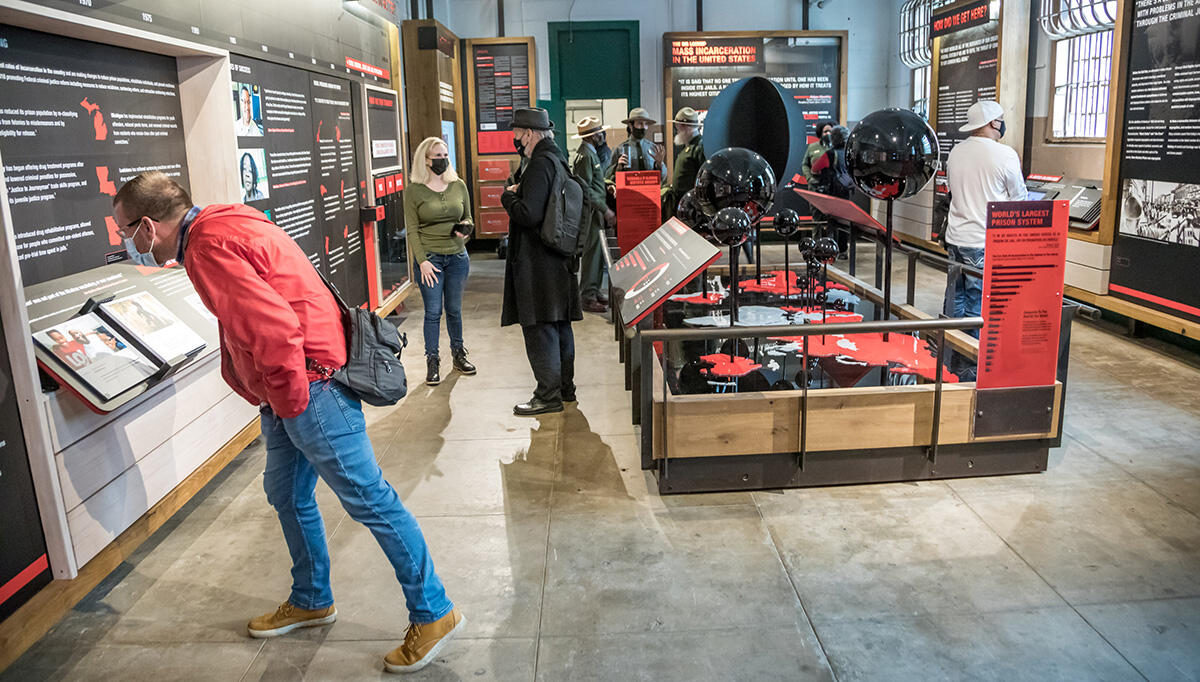 Visitors examine information about incarceration on red and black panels around the new 'Big Lockup' exhibit.