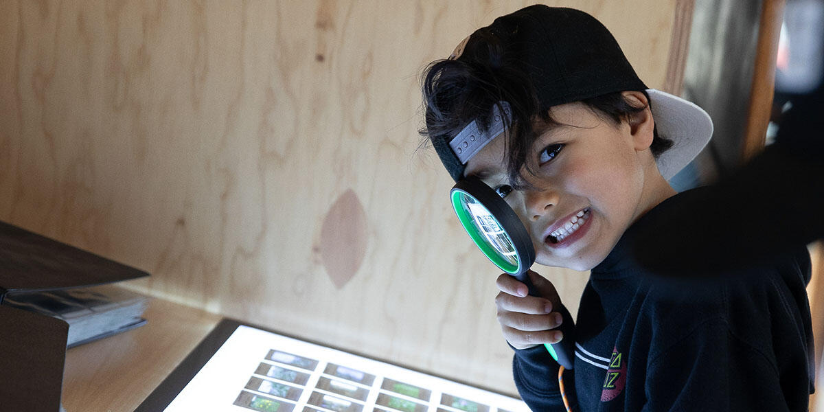 Youth with magnifying glass looking at slides at Presidio Tunnel Tops.