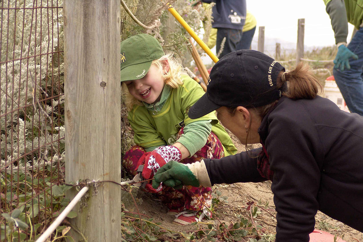 A child and her mother help plant native vegetation at Crissy Field