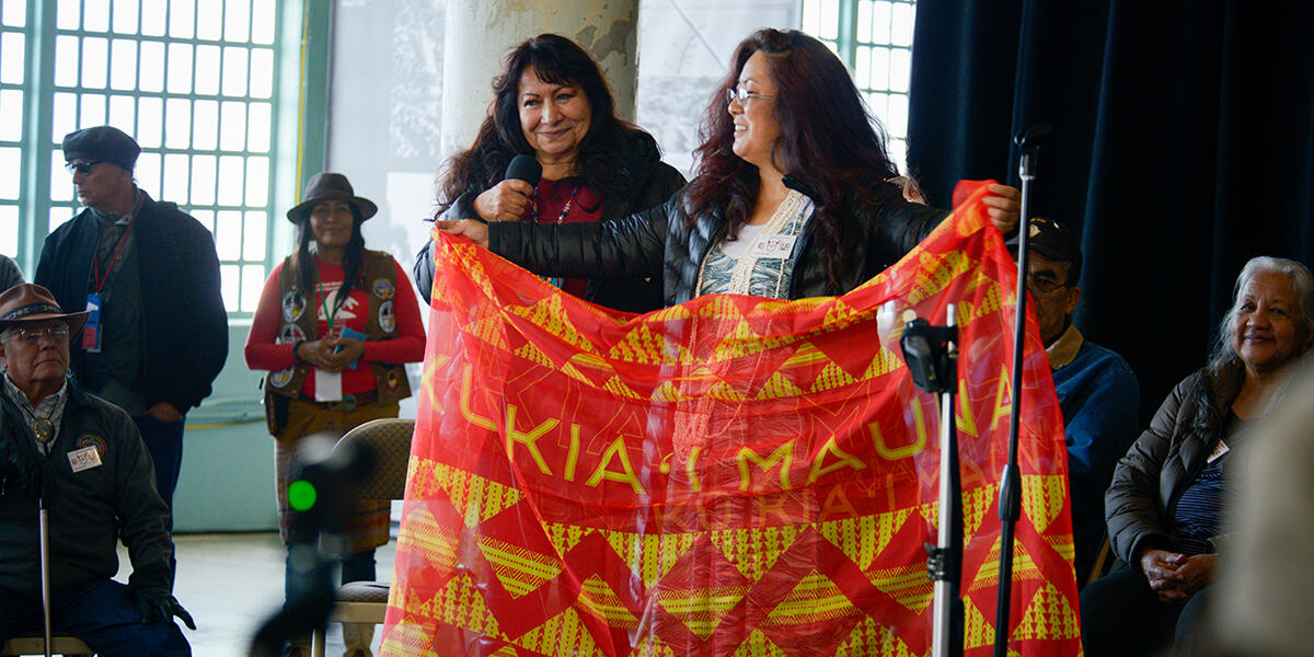 two woman on stage with banner