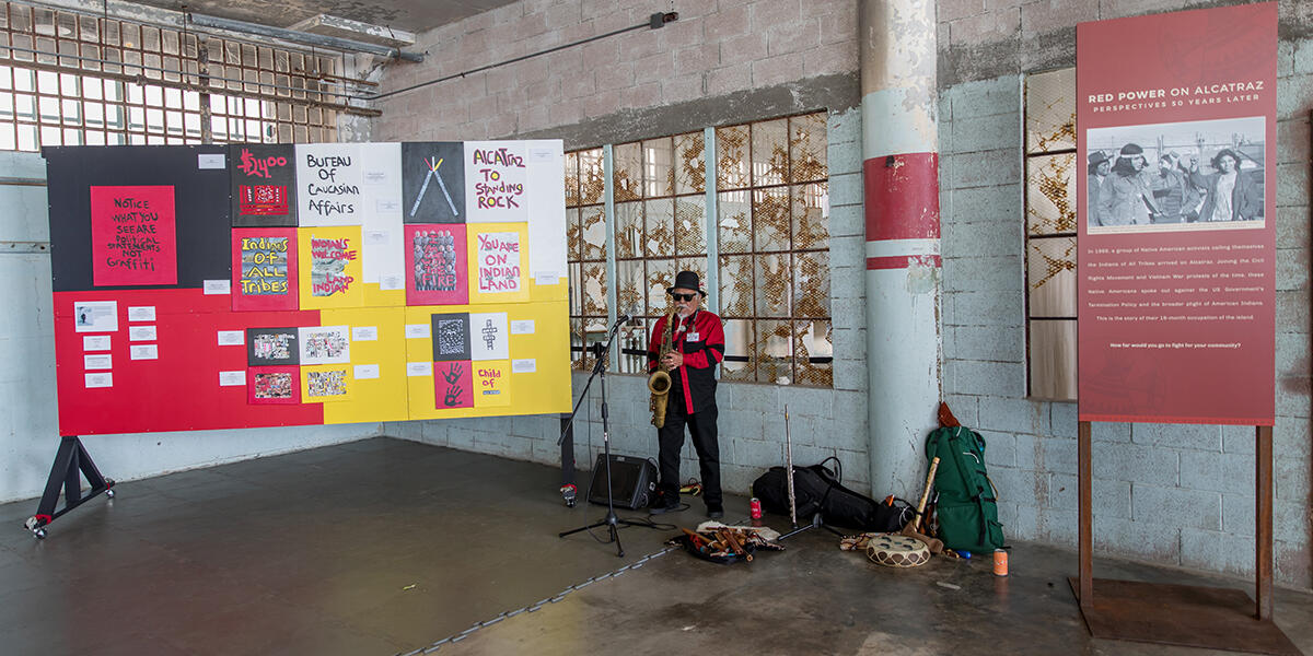 Man playing saxophone surrounded by slogans about Red Power on Alcatraz