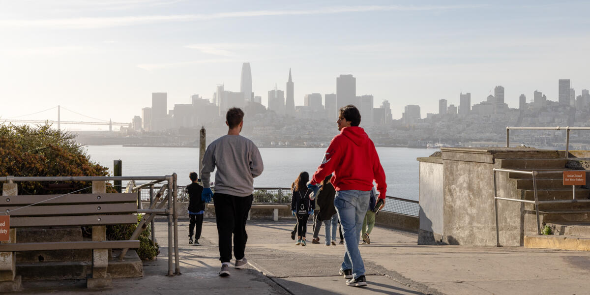 Students walk amid the San Francisco skyline on their way to Alcatraz Historic Gardens to volunteer.