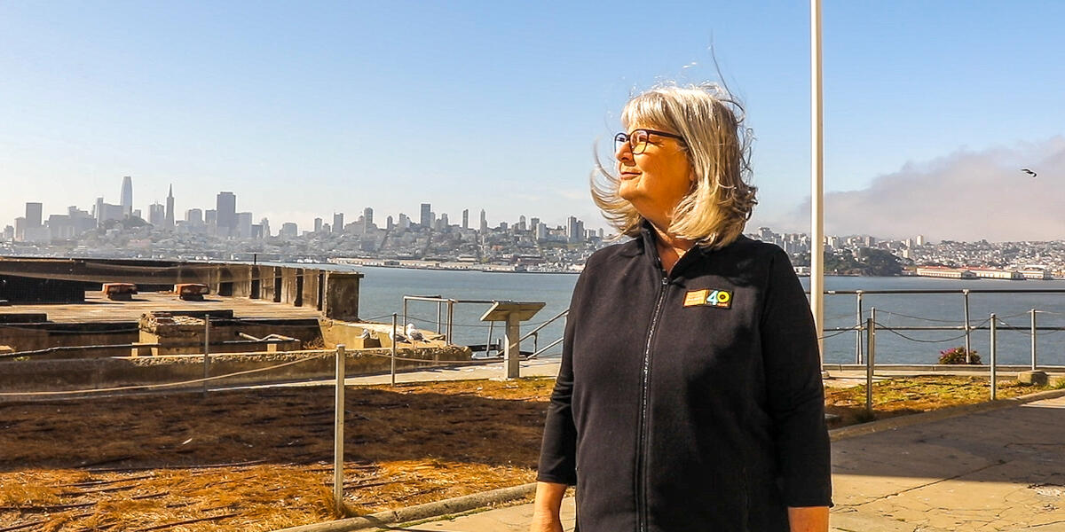 Portrait of Parks Conservancy staff member Nicki Phelps on Alcatraz Island with the San Francisco skyline backdrop