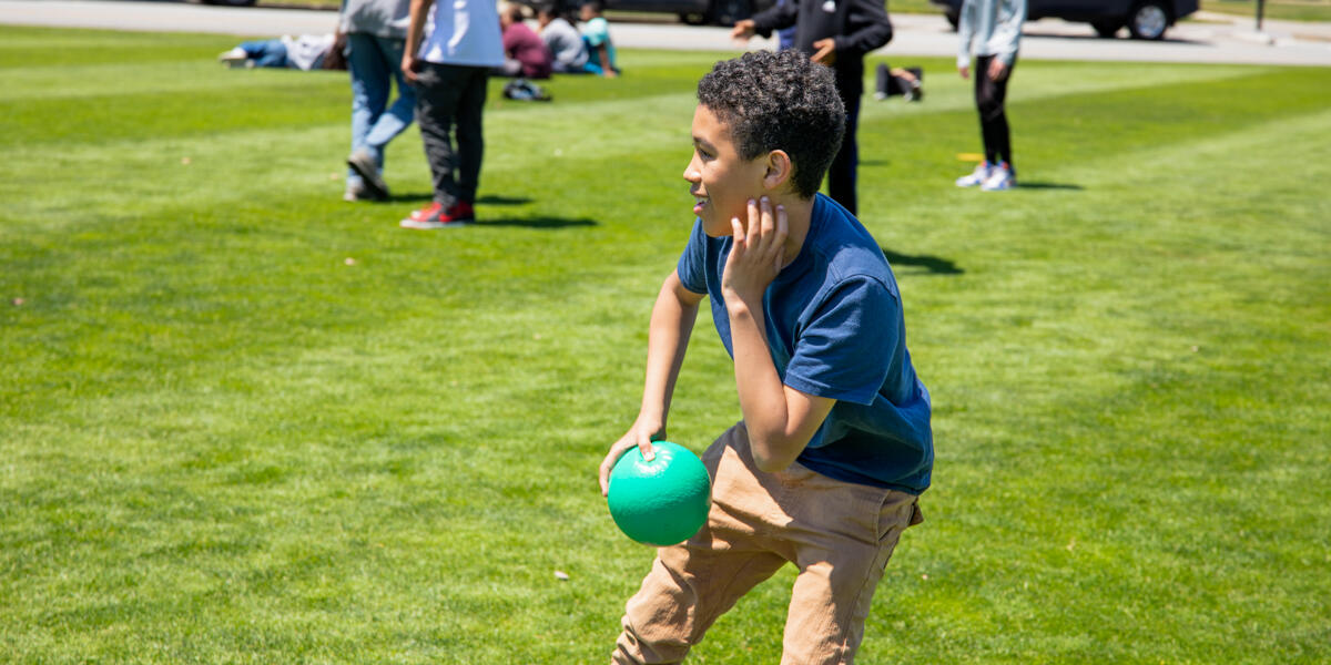 A youth participant of Crissy Field Center plays with a handball on the Presidio lawn.