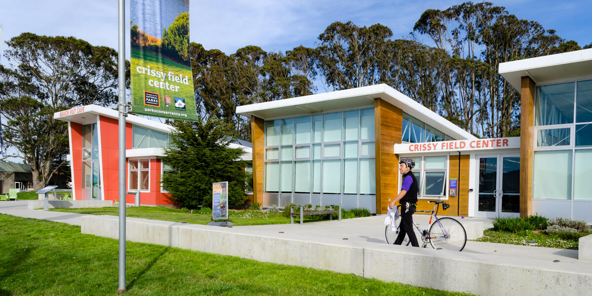 A park visitor at Crissy Field walks his bike by Crissy Field Center.