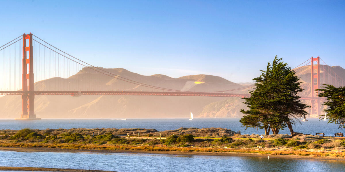 The Golden Gate Bridge as viewed from Crissy Field. The bay waters can be seen with sailboats about, as well as Crissy Marsh and the Marin Headlands.