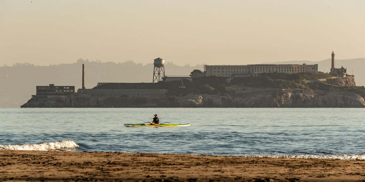 A Kayak paddles over the Golden Gate waters, viewed before Alcatraz Island from Crissy Field East Beach.