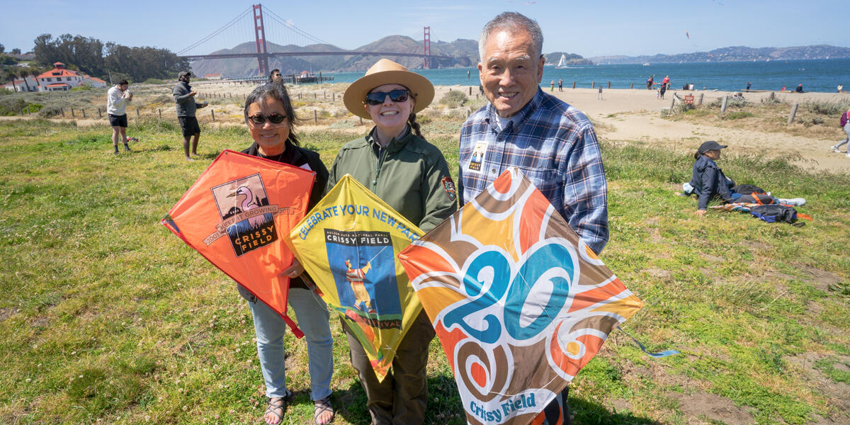 Conservancy, NPS, and community representatives pose with commemorative kites at Crissy Field Kite Day