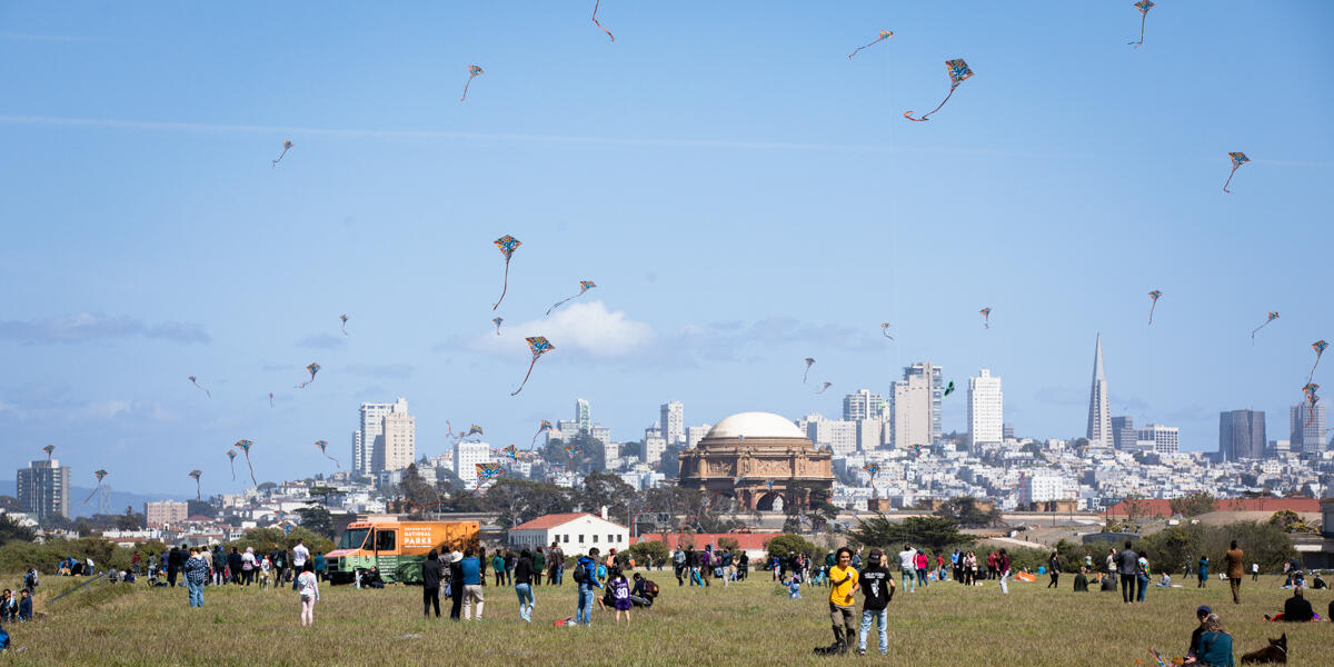 Many kites fill the sky at Crissy Field with crowds of park visitors recreating below.