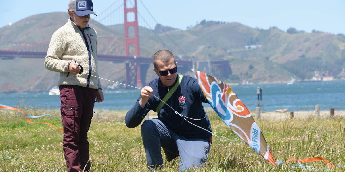 A parent helps their child with a kite at Crissy Field.
