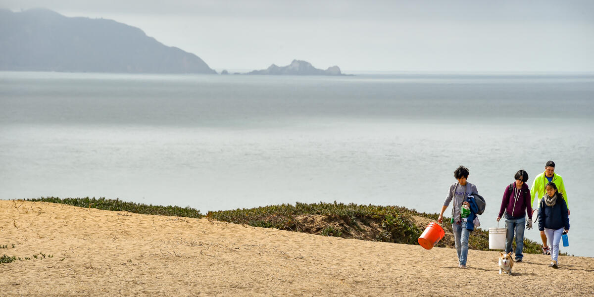 A family with their dog, walking in from the Fort Funston bluffs after volunteering for beach cleanup.