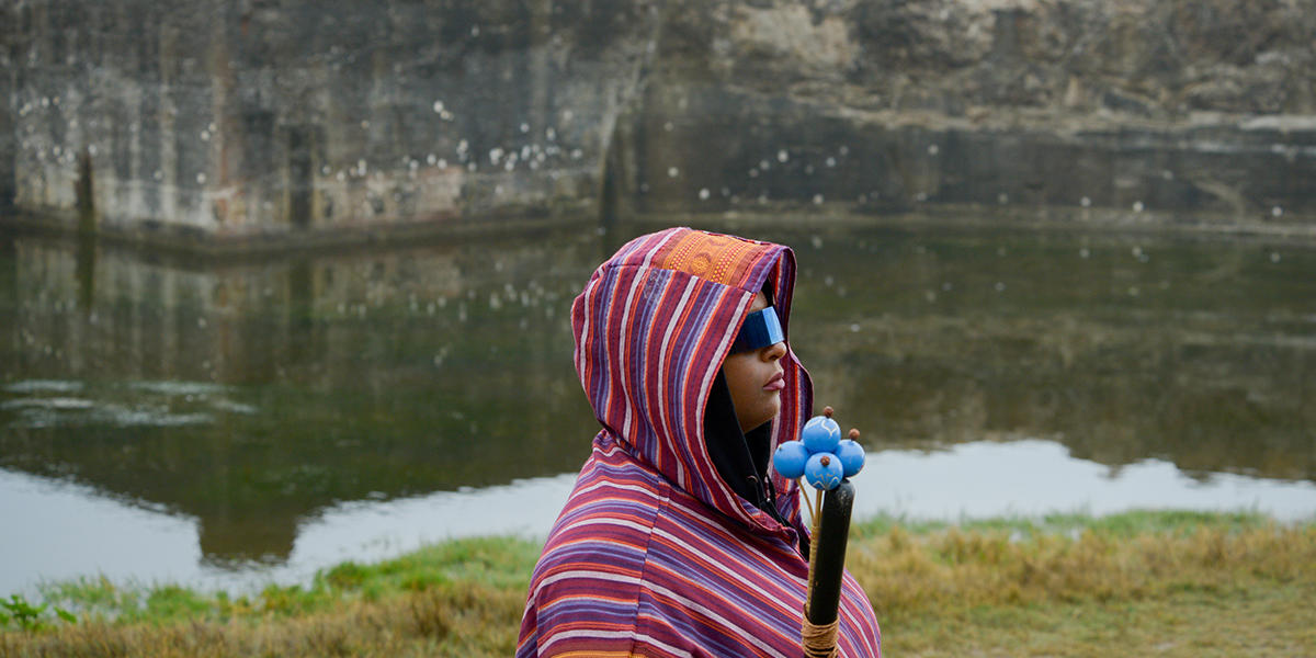 Woman wearing hood stands by water at Sutro Baths during "Tremble Staves."