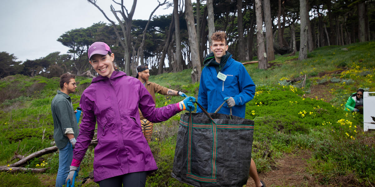 Two volunteers hold up bag full of weeds at Lands End in San Francisco