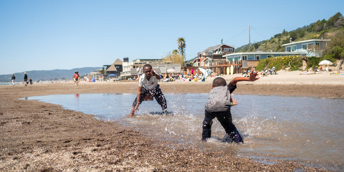 Two kids at play, splashing in the water on a sunny day at Stinson Beach