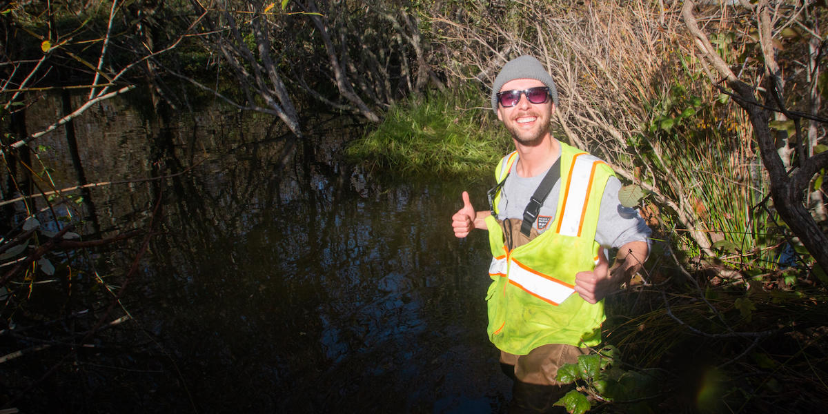 Person standing in Redwood Creek at Muir Beach with his thumbs up during a re-release of coho salmon.