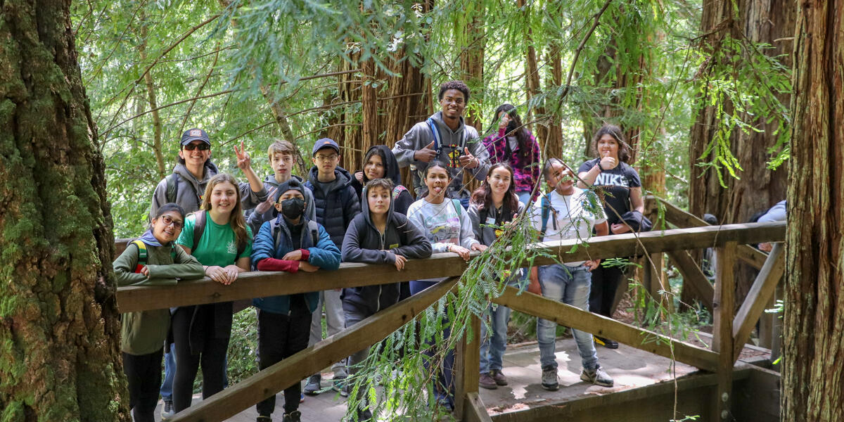 A group of Crissy Field Center Urban Trailblazers pose for a photo on a bridge in Muir Woods