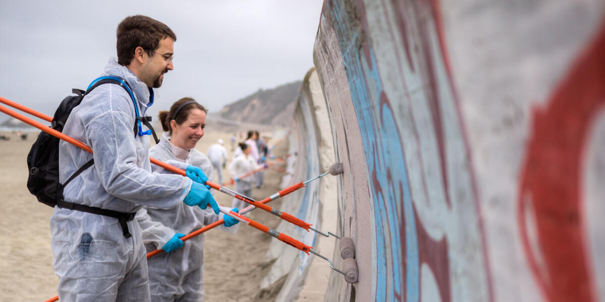 Park stewardship volunteers help to remove graffiti from the Ocean Beach seawall.