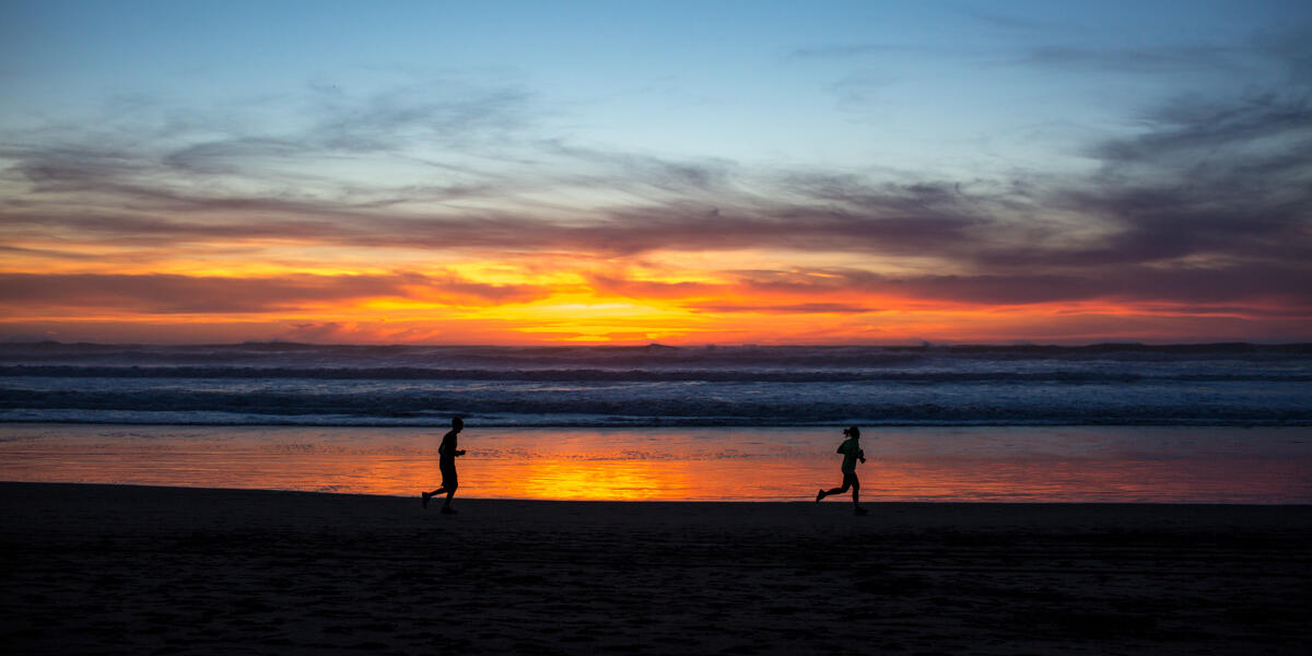 Park visitors are going for a jog along the gorgeous red sunset and lapping waves at Ocean Beach.