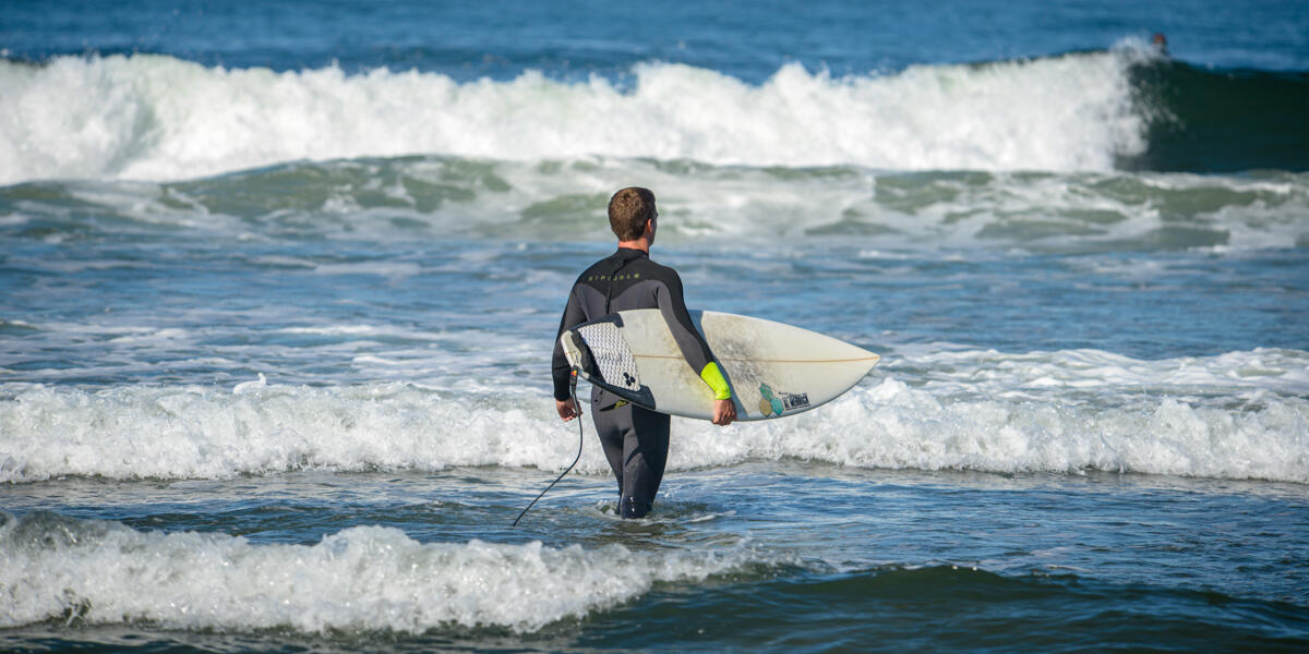 A surfer surveys the blue water and waves at Ocean Beach
