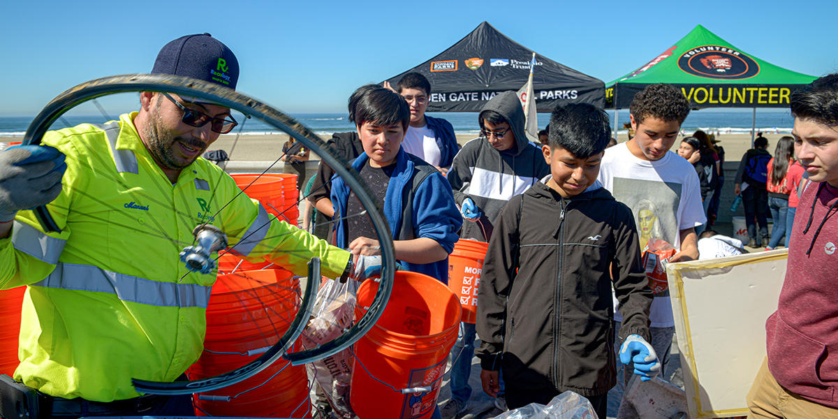 Reology worker puts bicyle wheel in trash bin. Taken during California Coastal Cleanup Day in Ocean Beach in San Francisco.