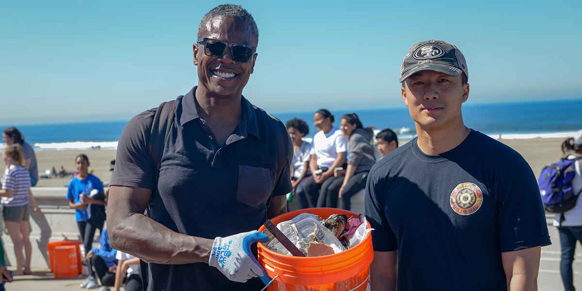 California Coastal Cleanup Day Volunteers pose with bucket of trash they collected from Ocean Beach in San Francisco.