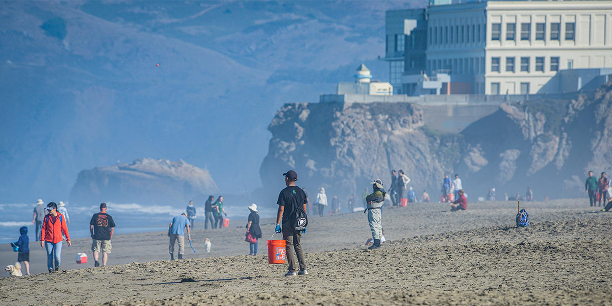 Crowd of volunteers on trash pickup duty on Ocean Beach in San Francisco.