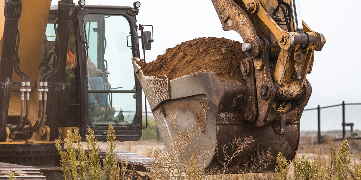 Excavator with dirt in bucket.