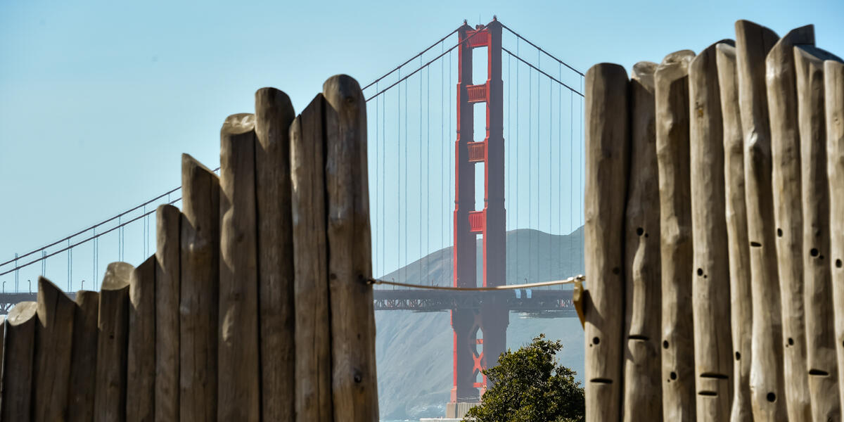 The Golden Gate Bridge is seen through the climbing wall of the Presidio Tunnel Tops Outpost playground.