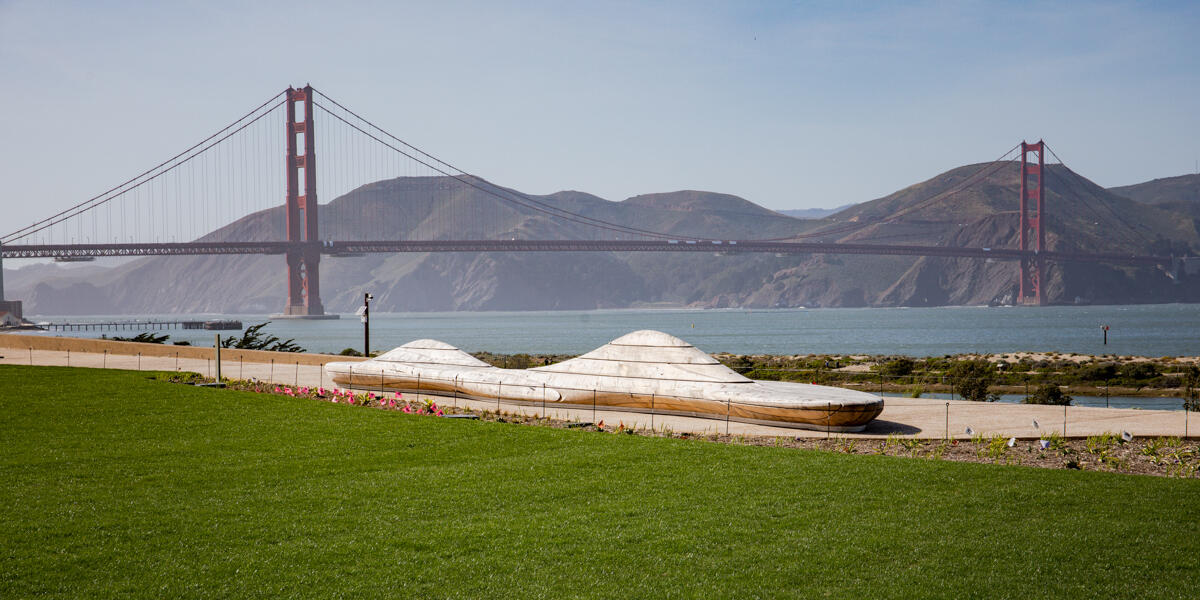 An artistically crafted bench at Presidio Tunnel Tops sits before the Golden Gate Bridge and Marin Headlands in the background.