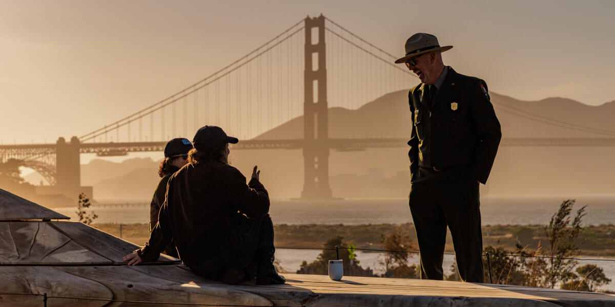 NPS ranger enjoying a conversation at the Presidio Tunnel Tops with the Golden Gate Bridge backdrop.