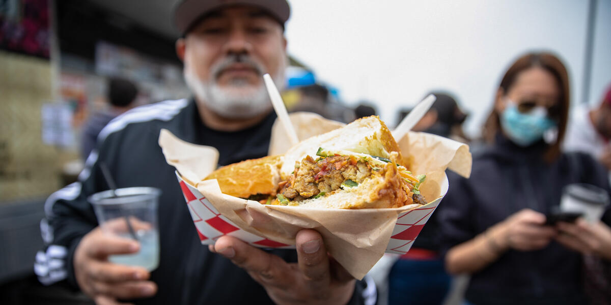 A Tunnel Tops visitor holds out a delicious gourmet sandwich from the food vendors at Presidio Tunnel Tops.